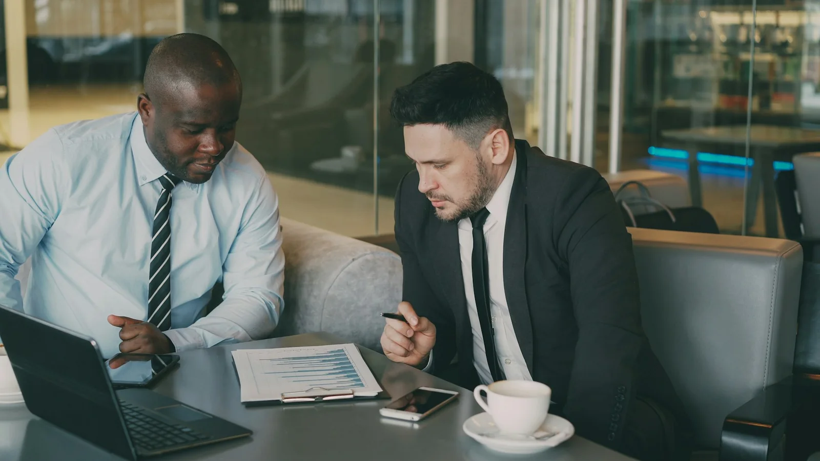 Two businesspeople looking at a chart beside a laptop.