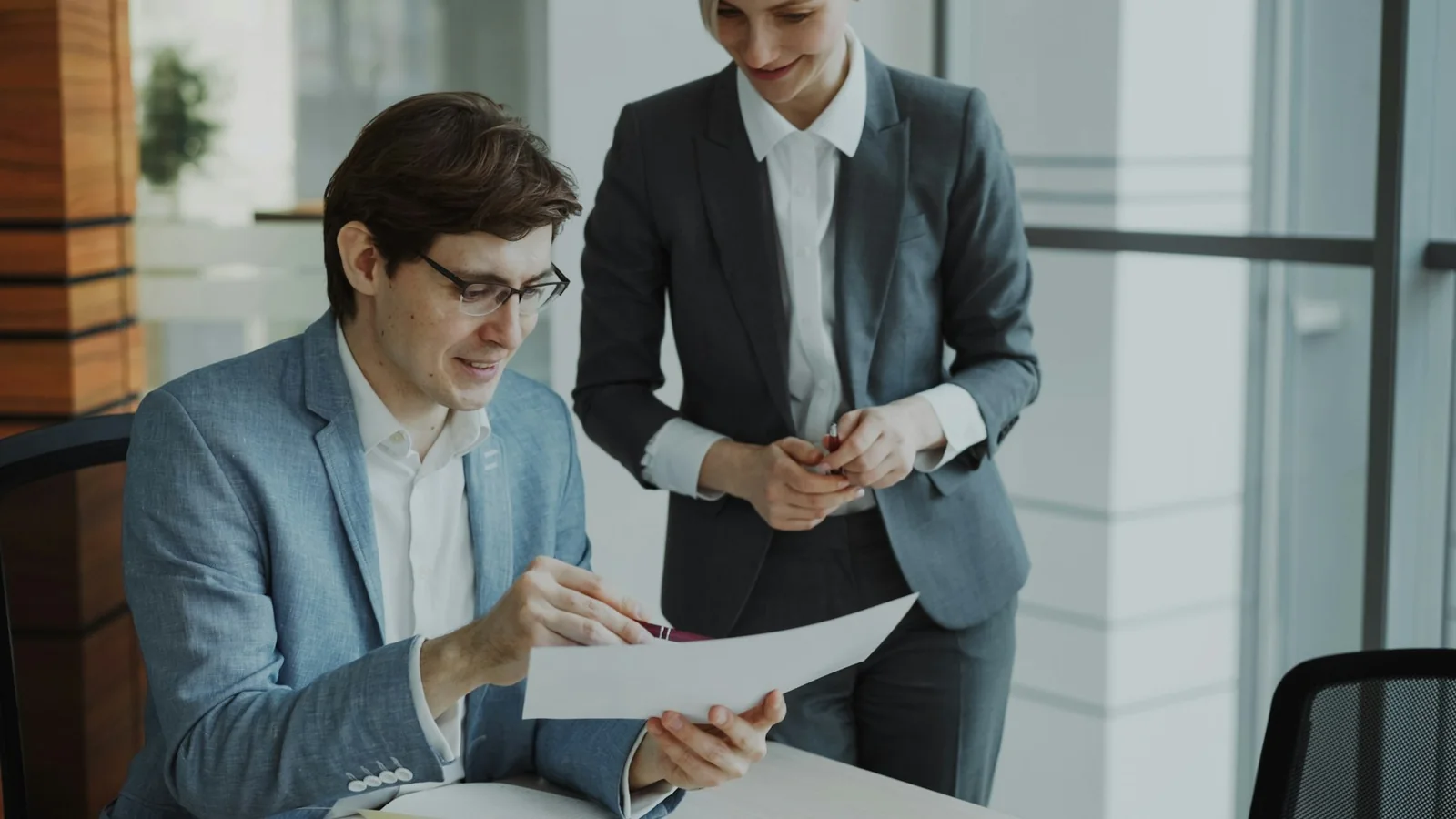 Two colleagues looking at a document in a bright office.